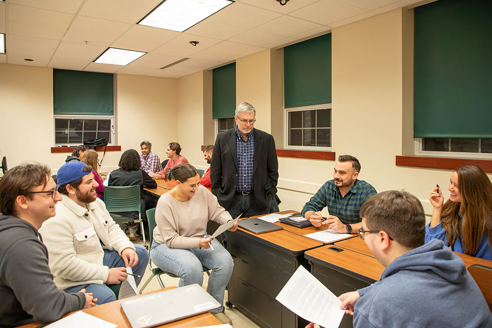A Siena professor participates in a group discussion with students during class.