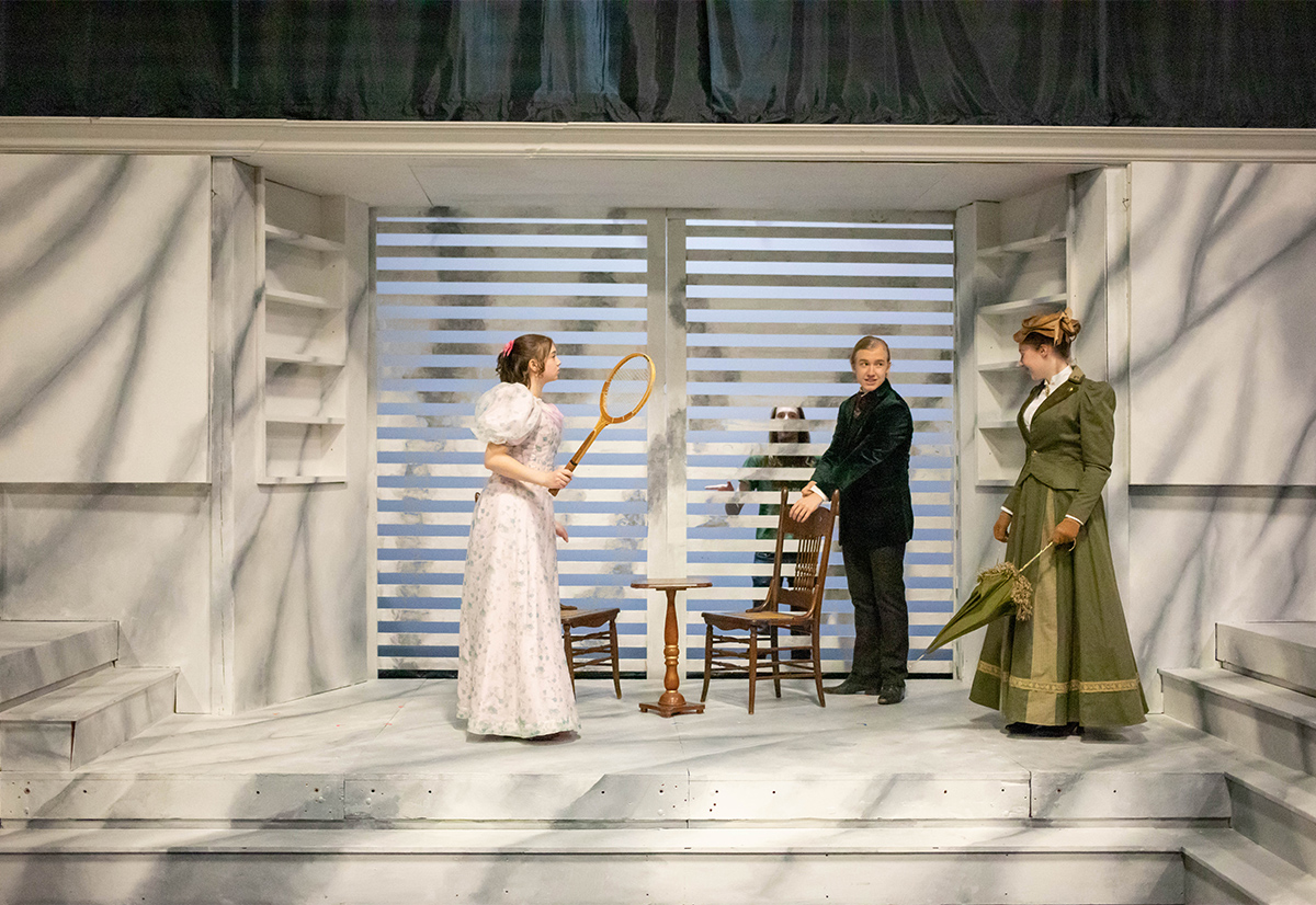 Three Siena students on a theatre stage dressed in Old English costumes.