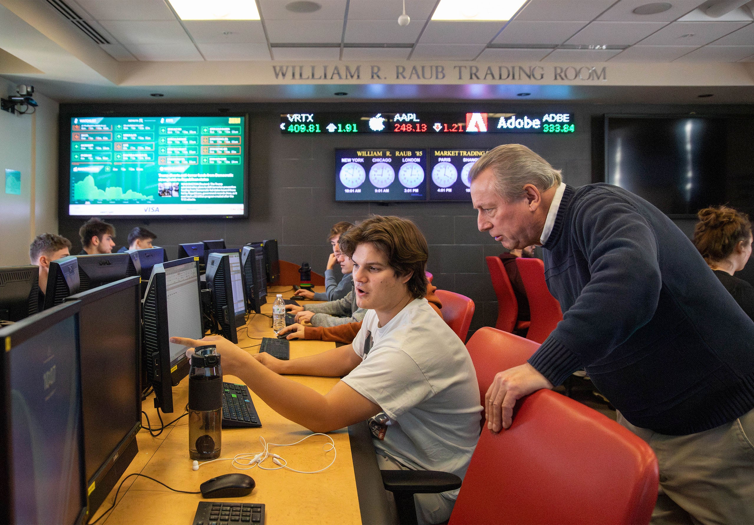 A Finance professor answers a question for a student in a computer lab.